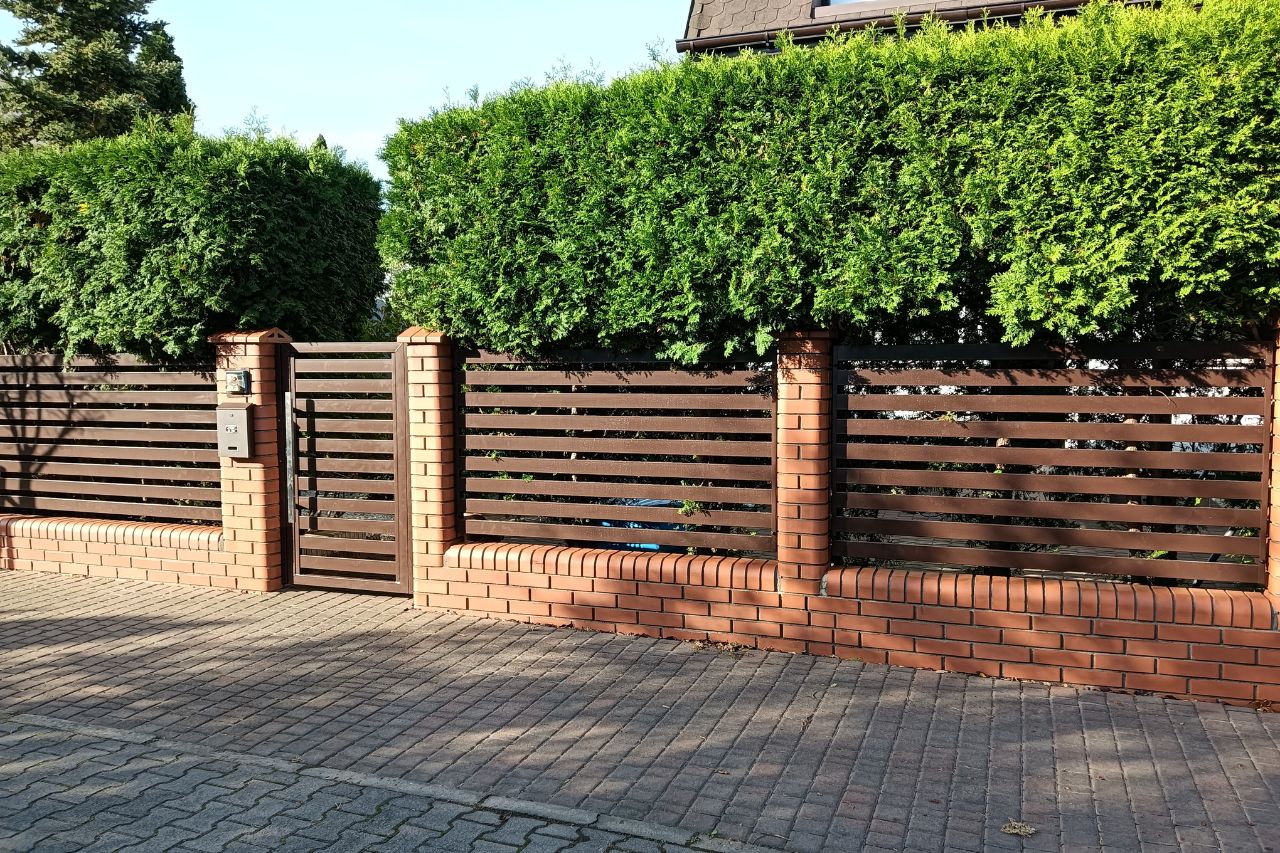ogrodzenie poziome z cegły i roślinnością przy domu